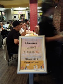 "Bienvenue - VOUILLEZ ATTENDRE _ICI_, S'il vous plaît! Please wait here." - a sign at the front of a restaurant we went to in Montréal